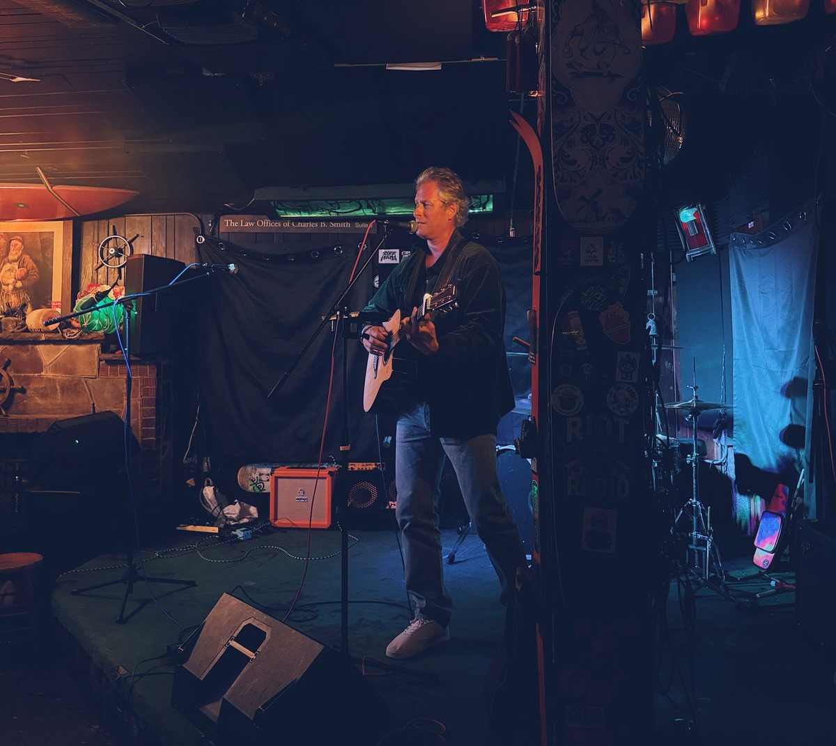 Pascal performing at a small venue with disco ball, drum kit and sticker-covered walls